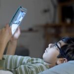 Young boy with glasses looking at a tablet.