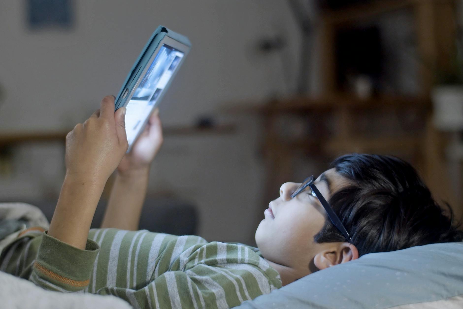 Young boy with glasses looking at a tablet.