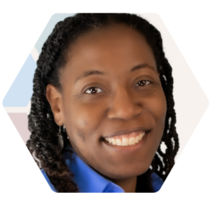 Smiling brown skinned woman with braids wearing a medium blue collared shirt.